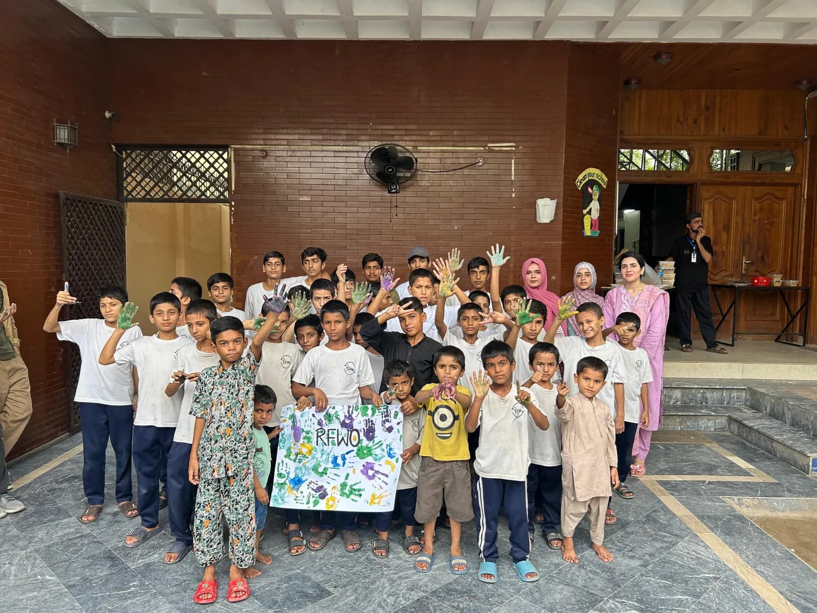 RFWO volunteers with children at ESRAH Orphanage holding a handprinted RFWO banner